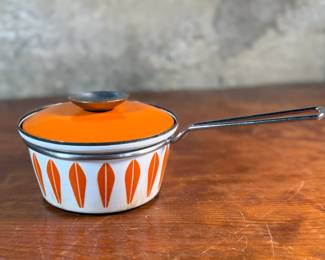 This lot features a vintage Cathrineholm Lotus enamel saucepan with a lid in an orange and white color scheme. The popular "Lotus" pattern was designed by Grete Prytz Kittelsen and produced during the early to mid-1960s in Norway.

