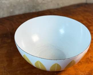 This lot features a vintage Cathrineholm Lotus enamelware bowl in white with a yellow (or mustard) leaf pattern. The design is a classic example of Mid-Century Modern Norwegian design. The bowl form and colors were created by designer Grete Prytz Kittelsen, while the iconic lotus pattern is attributed to Arne Clausen.

