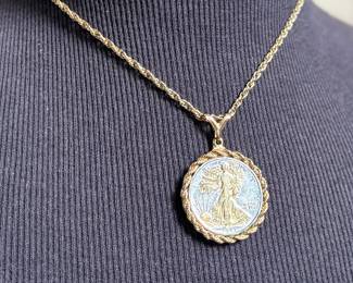 This lot features a gold-plated Walking Liberty pendant necklace that measures, 17”.

