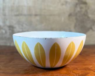 This lot features a vintage Cathrineholm Lotus enamelware bowl in white with a yellow (or mustard) leaf pattern. The design is a classic example of Mid-Century Modern Norwegian design. The bowl form and colors were created by designer Grete Prytz Kittelsen, while the iconic lotus pattern is attributed to Arne Clausen.

