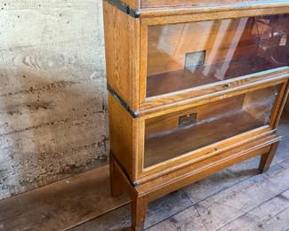 This lot features a stacking barrister bookcase manufactured by Globe Wernicke, dating back to the early 1900s. This bookcase in particular has a total of seven (7) pieces – 5 stacking bookcases, a base, and a topper. This piece measures from top to bottom, 79” H x 34” W x 11.5” D.


