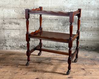 This lot features an antique English mahogany two-tier trolley or serving table, possibly Victorian era that measures, 30” H x 24” W x 16” D.

