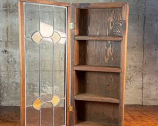 This lot features an antique spice cabinet with a stained glass door that measures, 22.5” H x 9.5” W x 4” D.

