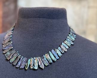 This lot features a peacock iridescent freshwater cultured Biwa pearl necklace with a 14k gold clasp marked 585. This necklace measures, 20”.

