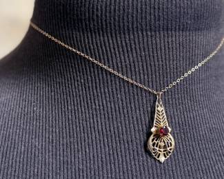 This lot features an antique 12k gold-filled silver filigree necklace with a red garnet gemstone. This necklace measures, 16”.

