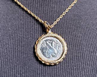 This lot features a gold-plated Walking Liberty pendant necklace that measures, 17”.

