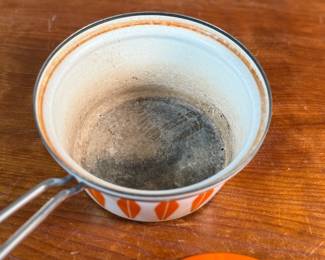 This lot features a vintage Cathrineholm Lotus enamel saucepan with a lid in an orange and white color scheme. The popular "Lotus" pattern was designed by Grete Prytz Kittelsen and produced during the early to mid-1960s in Norway.

