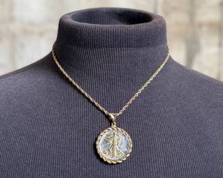 This lot features a gold-plated Walking Liberty pendant necklace that measures, 17”.

