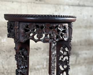 This lot features an antique Chinese carved rosewood marble-top plant stand that measures, 32” H x 13.5” W x 13.5” D. It features intricate carvings of leaf and floral motifs on the frieze, apron, and legs. These stands, also known as xiangji, are often considered antique or vintage pieces, with some dating back to the Republic Period (1912-1949).

