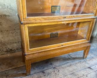 This lot features a stacking barrister bookcase manufactured by Globe Wernicke, dating back to the early 1900s. This bookcase in particular has a total of seven (7) pieces – 5 stacking bookcases, a base, and a topper. This piece measures from top to bottom, 79” H x 34” W x 11.5” D.

