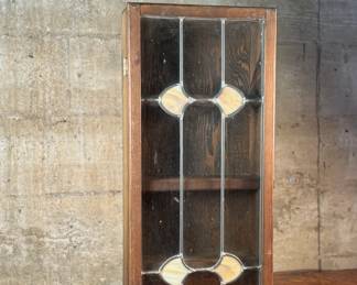 This lot features an antique spice cabinet with a stained glass door that measures, 22.5” H x 9.5” W x 4” D.

