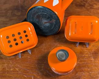 This lot features a vintage Cathrineholm Lotus coffee pot or kettle in orange enamel, accompanied by two matching orange enamel soap dishes. 

