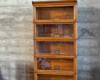 This lot features a stacking barrister bookcase manufactured by Globe Wernicke, dating back to the early 1900s. This bookcase in particular has a total of seven (7) pieces – 5 stacking bookcases, a base, and a topper. This piece measures from top to bottom, 79” H x 34” W x 11.5” D.

