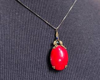 This lot features an antique sterling silver necklace with a red coral pendant. This necklace measures, 18”.

