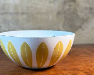 This lot features a vintage Cathrineholm Lotus enamelware bowl in white with a yellow (or mustard) leaf pattern. The design is a classic example of Mid-Century Modern Norwegian design. The bowl form and colors were created by designer Grete Prytz Kittelsen, while the iconic lotus pattern is attributed to Arne Clausen.


