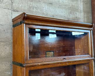 This lot features a stacking barrister bookcase manufactured by Globe Wernicke, dating back to the early 1900s. This bookcase in particular has a total of seven (7) pieces – 5 stacking bookcases, a base, and a topper. This piece measures from top to bottom, 79” H x 34” W x 11.5” D.

