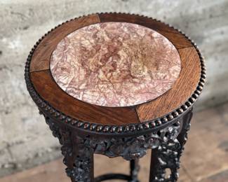 This lot features an antique Chinese carved rosewood marble-top plant stand that measures, 32” H x 13.5” W x 13.5” D. It features intricate carvings of leaf and floral motifs on the frieze, apron, and legs. These stands, also known as xiangji, are often considered antique or vintage pieces, with some dating back to the Republic Period (1912-1949).

