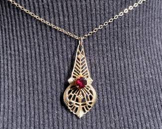 This lot features an antique 12k gold-filled silver filigree necklace with a red garnet gemstone. This necklace measures, 16”.

