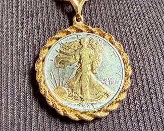 This lot features a gold-plated Walking Liberty pendant necklace that measures, 17”.

