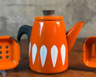 This lot features a vintage Cathrineholm Lotus coffee pot or kettle in orange enamel, accompanied by two matching orange enamel soap dishes. 

