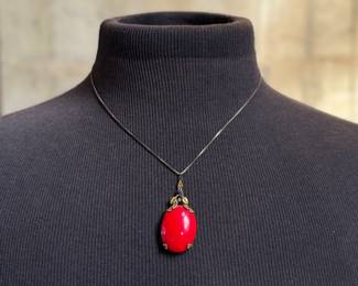 This lot features an antique sterling silver necklace with a red coral pendant. This necklace measures, 18”.

