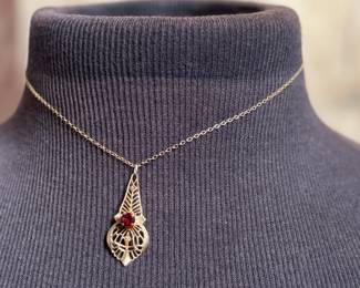 This lot features an antique 12k gold-filled silver filigree necklace with a red garnet gemstone. This necklace measures, 16”.


