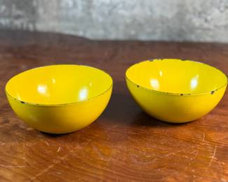 This lot features a pair of vintage Finel yellow enamel bowls, likely designed by Kaj Franck for the Finnish company Finel/Arabia during the 1950s or 1960s. Each bowl measures, 2.75” H x 6.25” W x 6.25” D.

