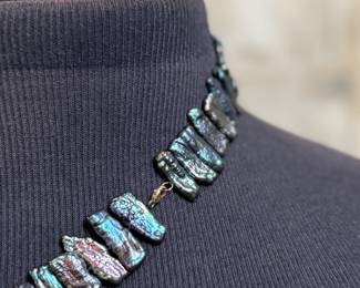 This lot features a peacock iridescent freshwater cultured Biwa pearl necklace with a 14k gold clasp marked 585. This necklace measures, 20”.

