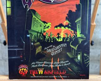This lot features a 1996 David Grisman Quintet concert poster for a "Birthday Bash" event at The Warfield in San Francisco. The event featured the David Grisman Quintet with special guests including Vassar Clements, Peter Rowan, Herb Pederson, and John Kahn. This poster is an original print from the Bill Graham Presents series, identified by the code BGP-139 and the artwork was created by artist, Jim Phillips. This poster measures, 19” H x 13” W.

