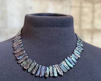 This lot features a peacock iridescent freshwater cultured Biwa pearl necklace with a 14k gold clasp marked 585. This necklace measures, 20”.

