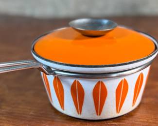 This lot features a vintage Cathrineholm Lotus enamel saucepan with a lid in an orange and white color scheme. The popular "Lotus" pattern was designed by Grete Prytz Kittelsen and produced during the early to mid-1960s in Norway.


