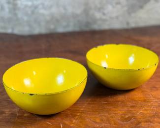 This lot features a pair of vintage Finel yellow enamel bowls, likely designed by Kaj Franck for the Finnish company Finel/Arabia during the 1950s or 1960s. Each bowl measures, 2.75” H x 6.25” W x 6.25” D.

