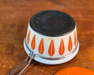 This lot features a vintage Cathrineholm Lotus enamel saucepan with a lid in an orange and white color scheme. The popular "Lotus" pattern was designed by Grete Prytz Kittelsen and produced during the early to mid-1960s in Norway.

