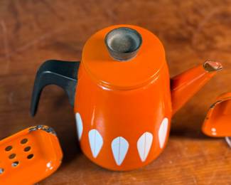 This lot features a vintage Cathrineholm Lotus coffee pot or kettle in orange enamel, accompanied by two matching orange enamel soap dishes. 

