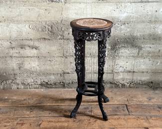 This lot features an antique Chinese carved rosewood marble-top plant stand that measures, 32” H x 13.5” W x 13.5” D. It features intricate carvings of leaf and floral motifs on the frieze, apron, and legs. These stands, also known as xiangji, are often considered antique or vintage pieces, with some dating back to the Republic Period (1912-1949).

