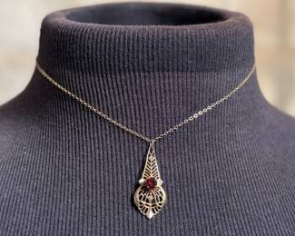 This lot features an antique 12k gold-filled silver filigree necklace with a red garnet gemstone. This necklace measures, 16”.

