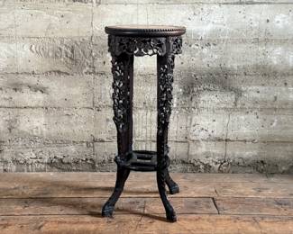 This lot features an antique Chinese carved rosewood marble-top plant stand that measures, 32” H x 13.5” W x 13.5” D. It features intricate carvings of leaf and floral motifs on the frieze, apron, and legs. These stands, also known as xiangji, are often considered antique or vintage pieces, with some dating back to the Republic Period (1912-1949).


