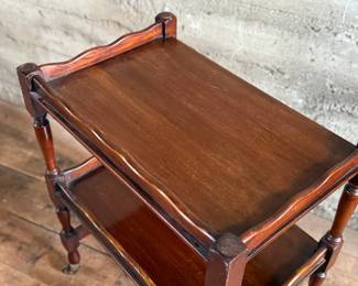This lot features an antique English mahogany two-tier trolley or serving table, possibly Victorian era that measures, 30” H x 24” W x 16” D.

