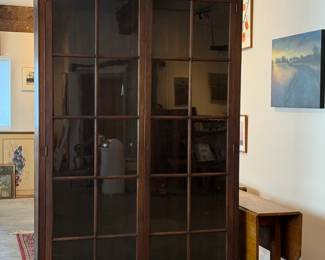 This lot features a large, solid wood cabinet with glass pane doors that measures, 84” H x 52” W x 13.5” D. This cabinet comes locked (no key) and without shelves.


