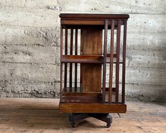 This lot features an antique Edwardian hardwood revolving bookcase, circa early 1900s, featuring vertical slatted sides and original castors. This bookcase measures, 33” H x 19” W x 19” D.


