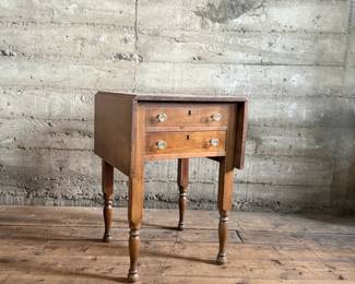 This lot features an antique drop-leaf side table with two dove-tailed drawers. This table measures (closed), 28.5” H x 19.5” W x 20.75” and each leaf adds an additional 11” of width. 

