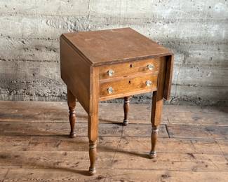 This lot features an antique drop-leaf side table with two dove-tailed drawers. This table measures (closed), 28.5” H x 19.5” W x 20.75” and each leaf adds an additional 11” of width. 

