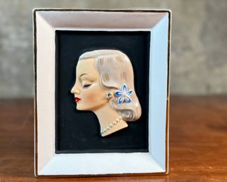 This lot features a vintage Napco Lady Head Vase (or wall pocket) from around 1958. These items were manufactured in Japan by the National Potteries Corporation (Napco) and were popular home decor items in the 1950s and 1960s. This vase measures, 6.5” H x 5.25” W x 2.75” D and is in very good condition.

