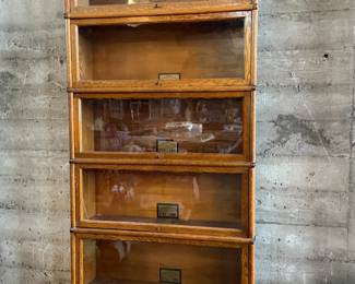 This lot features a stacking barrister bookcase manufactured by Globe Wernicke, dating back to the early 1900s. This bookcase in particular has a total of eight (8) pieces – 6 stacking bookcases, a base, and a topper. This piece measures from top to bottom, 90” H x 34” W x 11” D.

