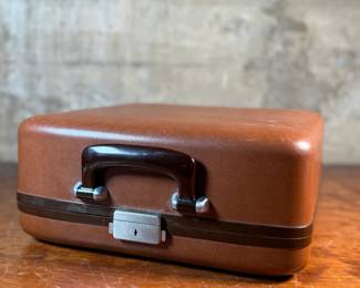 This lot features a vintage Smith Corona Silent-Super portable typewriter, circa 1950s. It has a khaki-toned body and forest green keys, and is shown with its original carrying case. 

