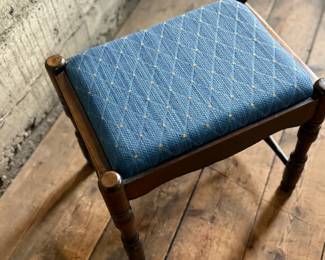 This lot features an antique English oak upholstered joint stool with turned legs and stretchers that measures, 16” H x 18” W x 13.5” D.

