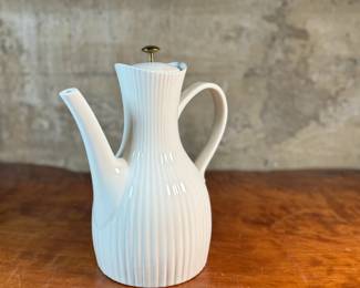 This lot features a vintage Ernest Sohn Creations "Doric" line white ribbed ceramic coffee server or teapot. It was designed by Ernest Sohn and produced by Hall China in the 1950s. This model typically holds around 10 to 12 cups of coffee or tea and measures, 12” H x 10” W x 6” D.

