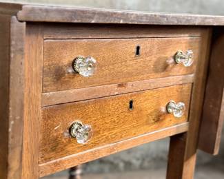 This lot features an antique drop-leaf side table with two dove-tailed drawers. This table measures (closed), 28.5” H x 19.5” W x 20.75” and each leaf adds an additional 11” of width. 

