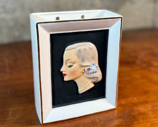 This lot features a vintage Napco Lady Head Vase (or wall pocket) from around 1958. These items were manufactured in Japan by the National Potteries Corporation (Napco) and were popular home decor items in the 1950s and 1960s. This vase measures, 6.5” H x 5.25” W x 2.75” D and is in very good condition.

