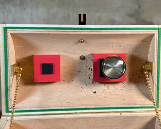 This lot features an original work of art by listed artist, Garry Knox Bennett. This piece is a uniquely designed humidor, signed by Bennett underneath circa 1997. This piece measures, 10” H x 11” W x 9” D. Born in Alameda, California, Garry Knox Bennett is a self-taught studio furniture maker who uses traditional fine woodworking techniques for both synthetic and natural materials. He attended the California College of Arts and Crafts in Oakland from 1959 to 1962 and then worked as a metal sculptor.

